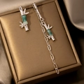 Macro detail of asymmetrical silver bamboo tassel earrings with green enamel on a gift box - Silver Bamboo Joint Asymmetric Earrings (E4836-1)