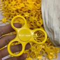 Three-leaf yellow plastic fidget spinner toy held by hand against a bulk stock background - Classic 3-Arm Frame Only with Bearing