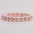 Macro detail of round 10mm pink shell pearls bracelet on a reflective white surface - Pink
