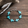 Detail of turquoise cross beaded bracelet with silver chain on dark wood background - Turquoise & Silver