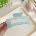 Light blue matte rectangular hair claw clip held over a tray with tulips - Blue