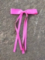 Pink satin ribbon hair bow clip with long streamers on a textured neutral background - Rose Red