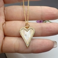 Macro shot of gold heart necklace with white mother of pearl inlay and zircon border - Mother of Pearl