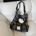 Detail of wool blend plaid bag with brown drawstring and white plush charm on sofa - Cream Bear Charm / Blue Green Grid