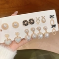 Close-up of elegant pearl and rhinestone earring set held against a warm wooden background - 2# Silver Needle-Gold-Black Flower Style (6 Pairs Set)