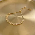 Adjustable golden tennis bracelet with yellow zircon stones on a dark textured background - Cross Slider Bracelet-Gold