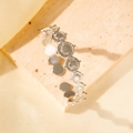 Silver open cuff bracelet with circular sunburst pattern on a stone display - Silver Sun Relief