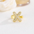 Dettaglio ravvicinato dell'anello incrociato dorato con zirconi pavé luccicanti - Lettera X