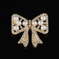 Gros plan sur la broche nœud dorée avec strass étincelants et perles d'imitation - Style B218