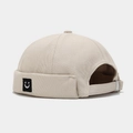 Vista de detalle de gorro docker beige con hebilla metálica ajustable y parche de cara - Ajustable / Beige