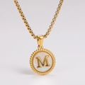 Macro shot of gold pendant with white shell inlay and letter M detail on box chain - Letter M