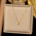Detail of a delicate gold heart pendant necklace on a beige jewelry display box - [XLH141] Patchwork Heart Necklace Gold