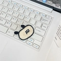 Close-up of a cute plush embroidered cartoon patch on a white laptop keyboard - Dog Head