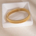 Détail d'un bracelet spirale doré multicouche avec texture métallique sur un support blanc - Bracelet jonc à texture rayée dense dorée
