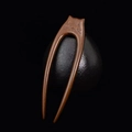 Macro shot of creative cat-shaped dark sandalwood hair pin on a textured black sphere - Double Prong Cat (Zebrawood)