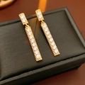 Detailed view of gold tassel earrings with zircon stones on a luxury jewelry box - Gold
