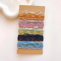 Detail of colorful elastic hair ties with bow accents on brown cardboard display - Bow Ribbed Set / 20 Pieces