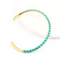 Detail of C-shaped gold-plated bangle with turquoise enamel inlay on a white pedestal - Lake Blue