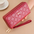 Macro shot of red leather wallet texture with embossed geometric patterns and golden H clasp - Red
