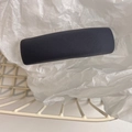 Detailed view of dark grey fabric hair clip with twill texture in a mesh basket - Gray