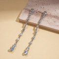 Nahaufnahme von silbernen Quastenohrringen mit Zirkonia auf einer Steinoberfläche - Versilbertes Kupfer / Zirkonia / 925 Silberstift / Silber