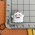 White cartoon ghost resin charm with red bow measured on a scale for size reference - Red Horns Ghost / Large