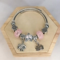 Detail of silver-colored elephant crown and pink carriage charms on a steel bracelet - Pink