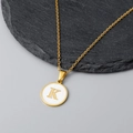 Detailed view of an 18K gold letter K shell pendant on a textured black stone - Letter K Style / Gold