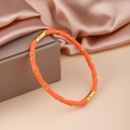 Schicker orangefarbener Bambus-Armreif mit Vergoldung auf elegantem Satin-Hintergrund - Orange