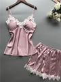 Close-up of pink satin pajama set with delicate white lace trim and thin straps - Pink