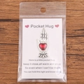 Pocket Hug token with red heart charm and silver hand base on motivational gift card - Silver Hand Holding Heart