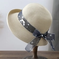 Summer straw sun hat with blue star ribbon and white bow on a wooden stand - Beige