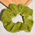 Detailed view of an avocado green velvet scrunchie on a decorative wooden tray - Fruit Green