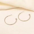 Detailed view of silver hoop earrings with round bead ends on a soft textured fabric - D131-Silver Ball Decorated Large Hoop / Silver