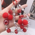 Close-up of red and white beaded phone strap with rhinestone accents and soft pom-pom - Red White Beaded