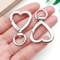 Silver heart lobster clasp with swivel ring shown in hand for size visualization - Heart Shape / White K / Silver