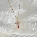 Detailed close-up of a colorful zircon cross pendant necklace on a minimalist book background - Cross Pendant / Gold-Multicolor