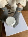 Dettaglio di guanti in maglia di cashmere grigi con etichetta in cuoio su tazza - Grigio