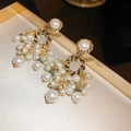 Golden flower earrings with white pearl tassels and twisted metal rings on a beige tray - Gold White Pearl Tassel