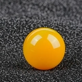 Polished round yellow cat eye stone ball bead with smooth reflective finish on black surface - Topaz
