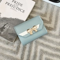 Detail of light blue tri-fold wallet with gold bow hardware and white V-stitch leather trim - Blue