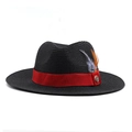 Close-up of black straw sun hat with red ribbon, colorful feathers and metal badge detail - Black