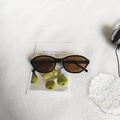 Gafas de sol ovaladas retro con montura negra y lentes marrones sobre postal - Marrón Oscuro