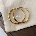 Detailed view of 5cm gold metal hoop earrings on textured fabric background - 50mm / Gold