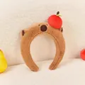 Detail der weichen Plüschtextur des Capybara-Stirnbands mit einem roten Plüschapfel oben - Capybara mit Apfel