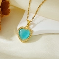 Detail of a golden heart necklace with teal cat-eye stone and sparkling zircon border - Gold Blue Stone Heart Necklace (T021)