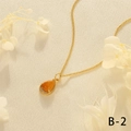 Detailed close-up of a 18K gold-plated teardrop necklace with an orange gemstone pendant - Topaz
