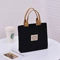 Mini black canvas tote bag featuring brown woven handles and a cute bear patch - Black