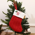 Red knitted Christmas stocking featuring white cuff with embroidered letter W and holly leaves - Letter W