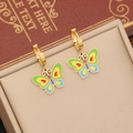 Detail of gold butterfly earrings with colorful enamel wings on a jewelry pad - Earrings